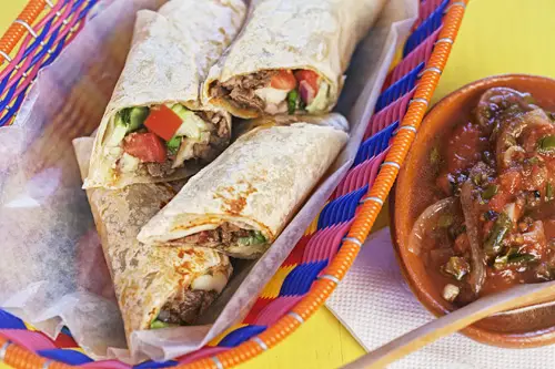 Burritos de Carne Asada servidos sobre una canasta y acompañados con salsa